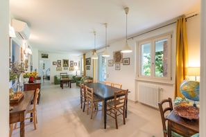A dining area with a table and chairs, a globe on a side table, and a window with curtains. - ApartmentsGarda - Cottage Capre (GARDA)