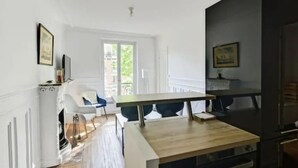 Moderni keittiö, jossa on puinen pöytä, valkoiset kaapit ja sisäänrakennettu uuni.