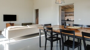 A modern living room with a sofa, dining table, chairs, and a TV. - Villa 'Loft' with Shared Pool, Wi-Fi and Air Conditioning (Cortona)
