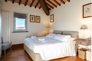 Une chambre à coucher avec un lit, des lampes de chevet, une fenêtre et des tableaux encadrés accrochés au mur.