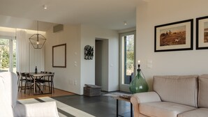 A modern living room with a sofa, a dining table with chairs, a hanging light fixture, and framed pictures on the wall. - Villa 'Residenza 2' with Shared Pool, Wi-Fi and Air Conditioning (Cortona)