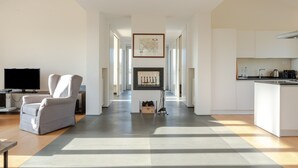 A spacious living area with a sofa, a flat-screen TV, a framed map on the wall, and a kitchen with white cabinets. - Villa 'Residenza 2' with Shared Pool, Wi-Fi and Air Conditioning (Cortona)