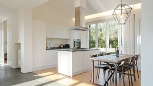A modern kitchen with a central island, a dining area with a wooden table and chairs, and large windows allowing natural light. - Villa 'Residenza 2' with Shared Pool, Wi-Fi and Air Conditioning (Cortona)