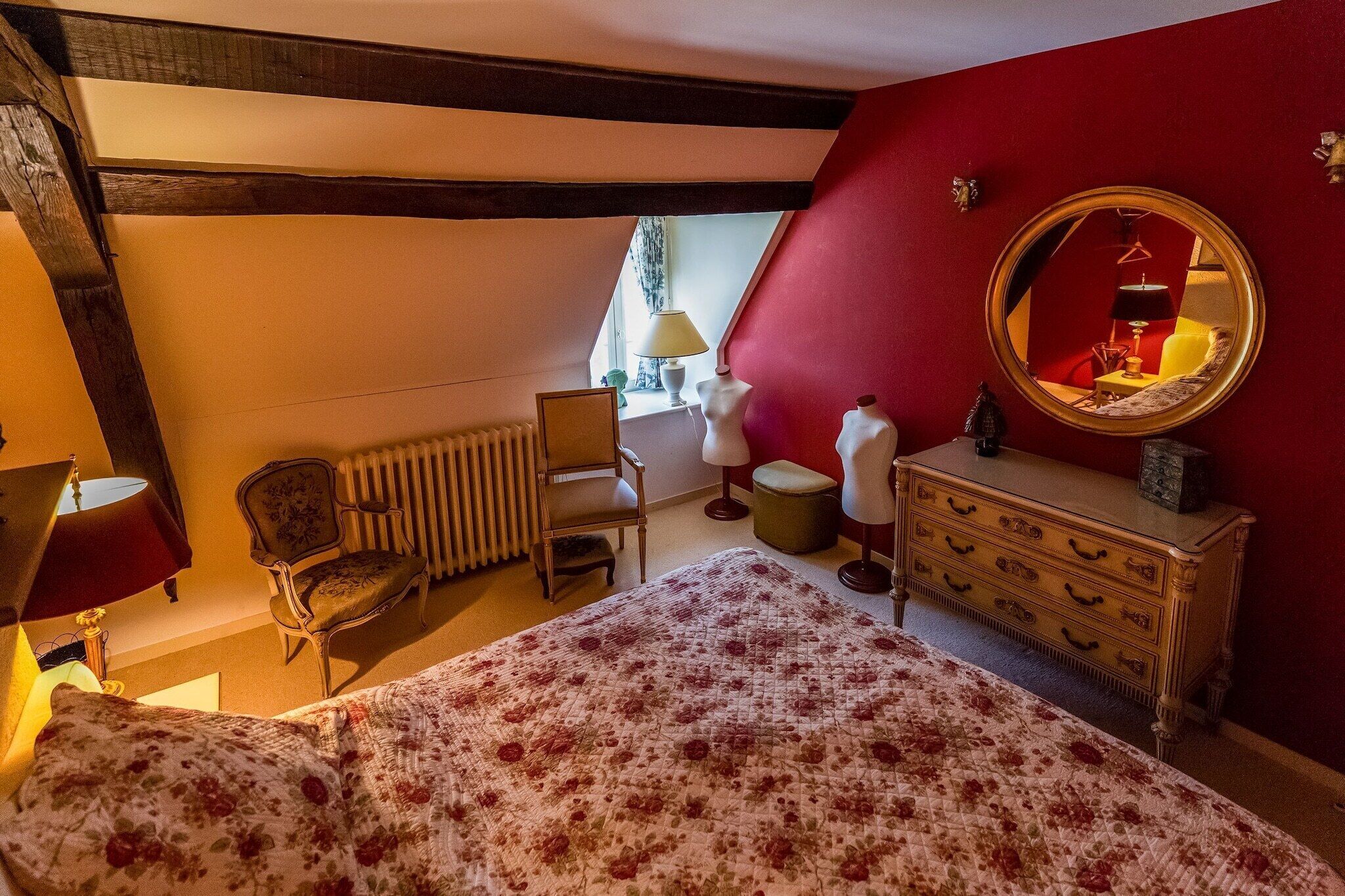 Un dormitorio con cama, cómoda, silla, lámpara y ventana.