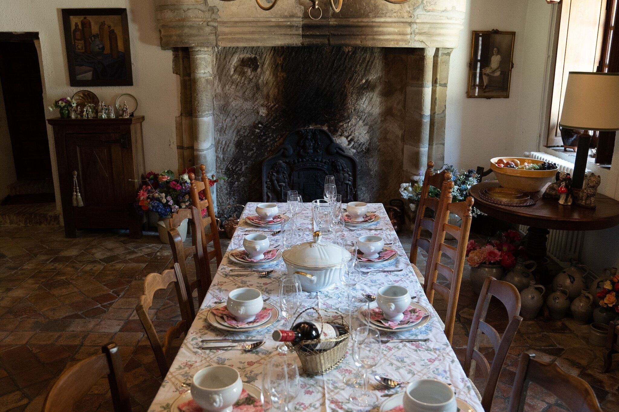 A dining room with a long table set for a meal, a fireplace, and various decorative items.