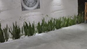 Una pared de concreto con un ventanal circular y dos luces empotradas.