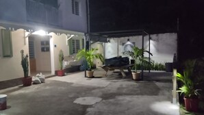 Un patio con plantas en macetas, un área de estar cubierta y la entrada de un edificio.