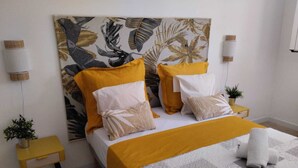 Un dormitorio ordenado con una cama grande, dos mesitas de noche y una lámpara de pared.