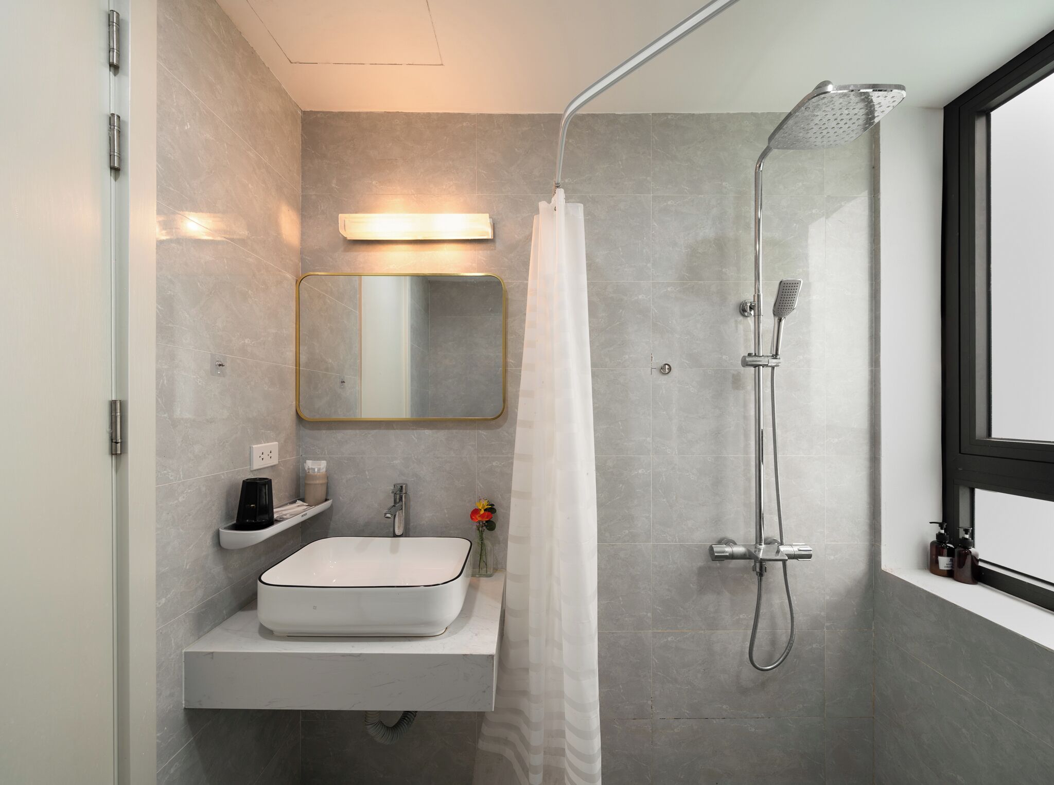 A modern bathroom with a built-in sink, a shower with a handheld showerhead, and a mirror with a light above it.
