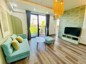 A modern living room with a sofa, ottoman, and a flat-screen TV on a stand. - Luxe Paradise Residence 76 To Ngoc Van (Hanoi)