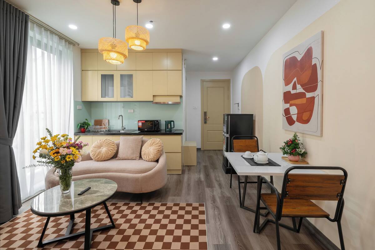 A modern living room with a sofa, a dining table, and a kitchen in the background.