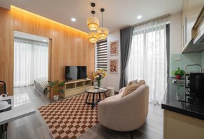 A modern living room with a sofa, TV, and a dining area with a table and chairs. - Luxe Paradise Residence 76 To Ngoc Van (Hanoi)