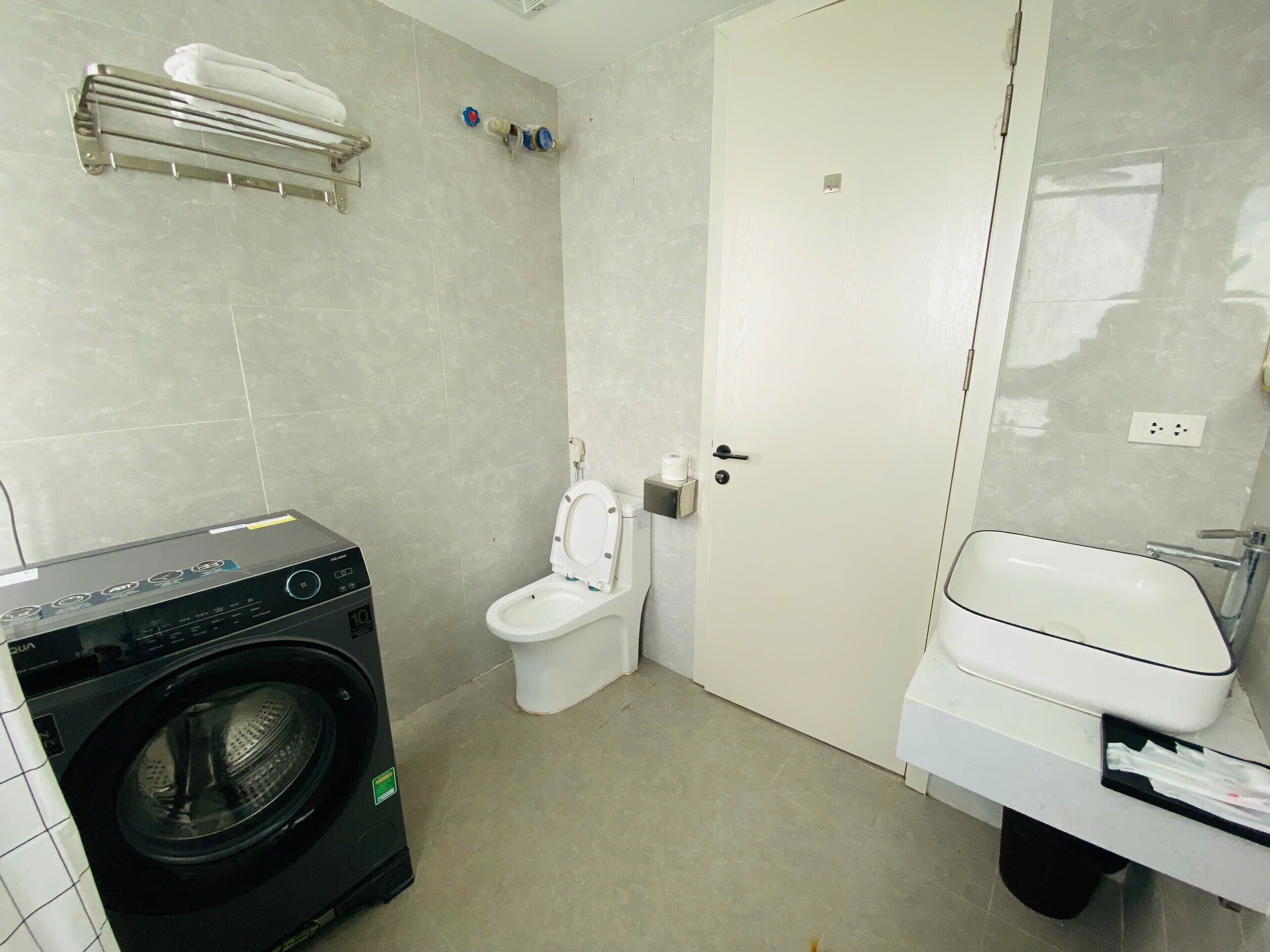 A compact bathroom with a washing machine, toilet, and sink.