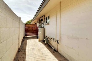 Outdoor space with a paved walkway, water tank, and hose for convenient access.