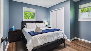 Een slaapkamer met een bed, nachtkastje en een deur.