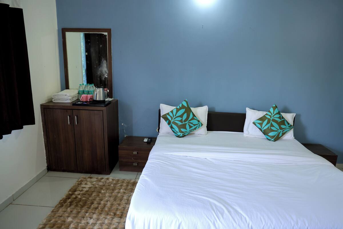 A bedroom with a bed, a wardrobe, a nightstand, and a mirror.