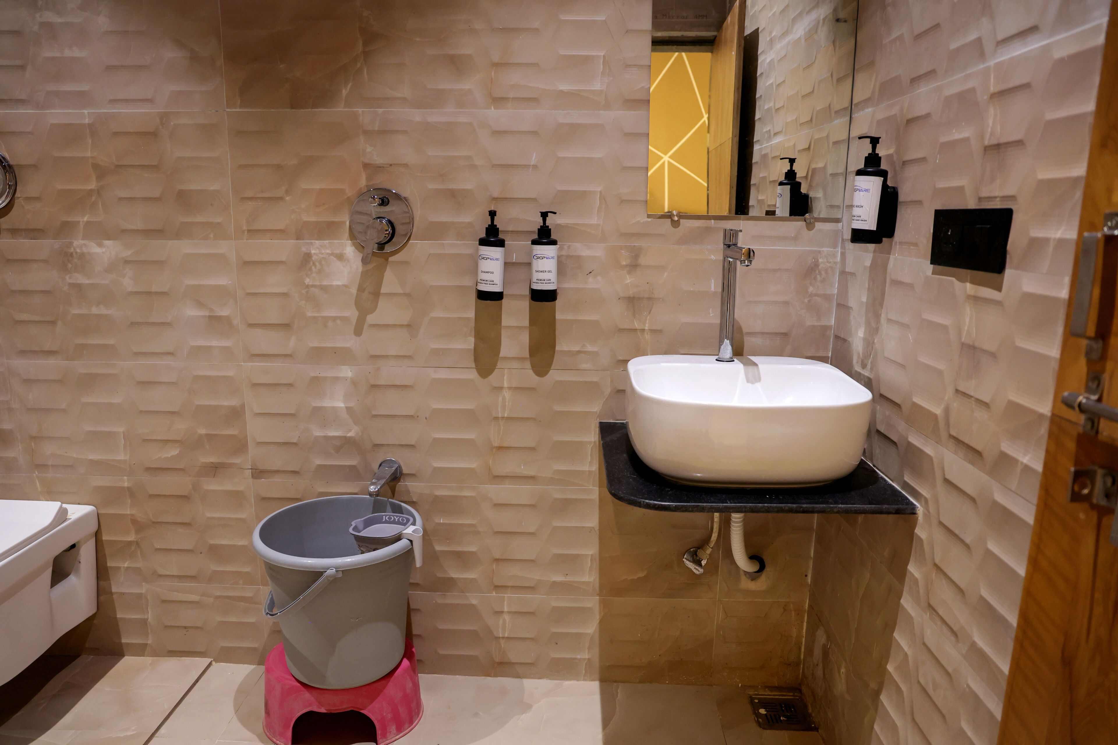 Un baño con un lavabo blanco, un bidé y dos dispensadores de jabón para manos en la pared.