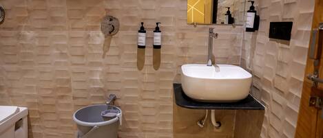 Un baño con un lavabo blanco, un bidé y dos dispensadores de jabón para manos en la pared.