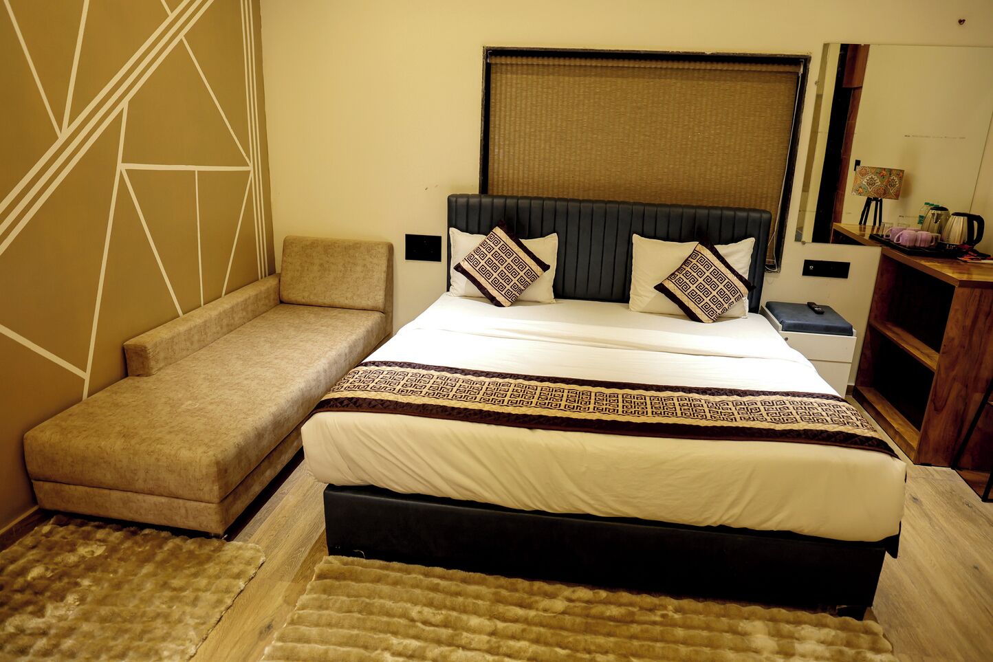 A bedroom with a bed, a sofa, a nightstand, and a wooden cabinet.