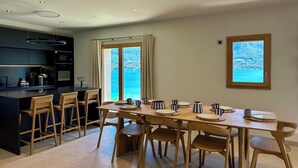 A modern kitchen with a central island, wooden chairs, and a dining table set for six. - Modern duplex with panoramic lake view & 100m from cycle path (Sévrier)