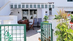 A patio with a table and chairs, a small staircase, and a gate with a plant in the foreground. - Casa Doralucia - Confortevole Casa Vacanze A Santa Maria Di Leuca (Castrignano del Capo)