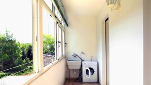A laundry room with a washing machine and sink, large windows, and a view of greenery outside. - Casa Doralucia - Confortevole Casa Vacanze A Santa Maria Di Leuca (Castrignano del Capo)