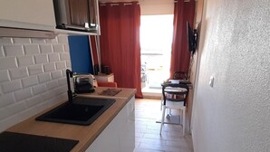 Une petite cuisine équipée d’un grille-pain, d’un évier et d’une fenêtre avec des rideaux.