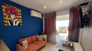 Une pièce comprenant un canapé, une table à manger avec des chaises, un appareil de climatisation et un tableau accroché au mur.