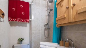 A bathroom with a shower, toilet, sink, and wooden cabinets. - Alpine mezzanine studio, sleeps 4, pets allowed, optional parking (Valmorel)