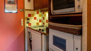 A compact kitchen with a built-in oven, a microwave, and a sink. - Alpine mezzanine studio, sleeps 4, pets allowed, optional parking (Valmorel)