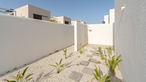 A modern outdoor space with a white wall, a gravel pathway, and small plants. - Villa Santorini (San Fulgencio) (San Fulgencio)