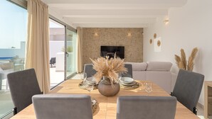 A modern dining area with a wooden table, grey upholstered chairs, and a vase of dried flowers. - Villa Santorini (San Fulgencio) (San Fulgencio)