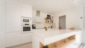 A modern kitchen with white cabinetry, a central island, and built-in appliances. - Villa Santorini (San Fulgencio) (San Fulgencio)