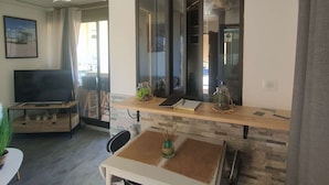 Een moderne woonkamer met een flatscreen-tv, een eettafel en een groot raam met uitzicht.