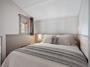 A bedroom with a bed, a window with curtains, and a bedside lamp. - 62m² Duplex near slopes with wellness area & wifi (Val Thorens)
