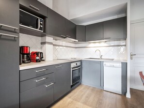 A modern kitchen with grey cabinets, a microwave, a coffee maker, an oven, and a dishwasher. - 62m² Duplex near slopes with wellness area & wifi (Val Thorens)