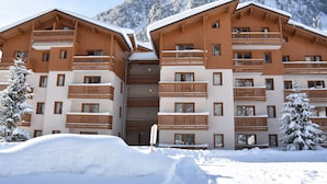 Un hôtel à plusieurs étages, doté de balcons en bois et surplombant un paysage montagneux.