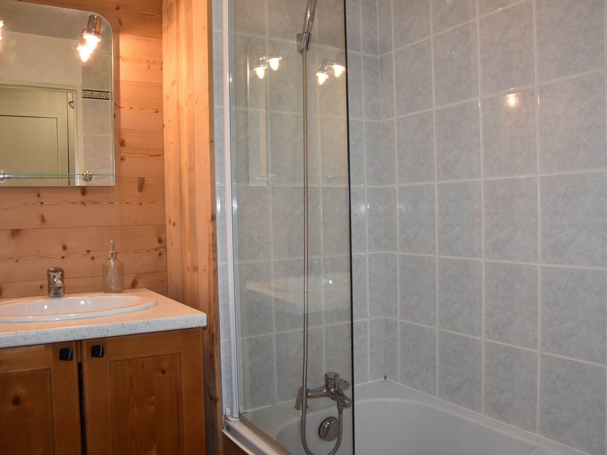A bathroom with a wooden vanity, a glass shower enclosure, and a bathtub.