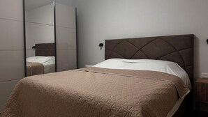 A bedroom with a bed, a mirror, and a nightstand. - Apartments Robi 2 (Rovinj)