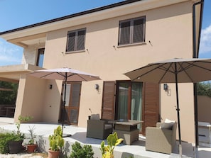 A modern two-story house with a patio area featuring outdoor furniture and umbrellas. - Apartments Robi 2 (Rovinj)