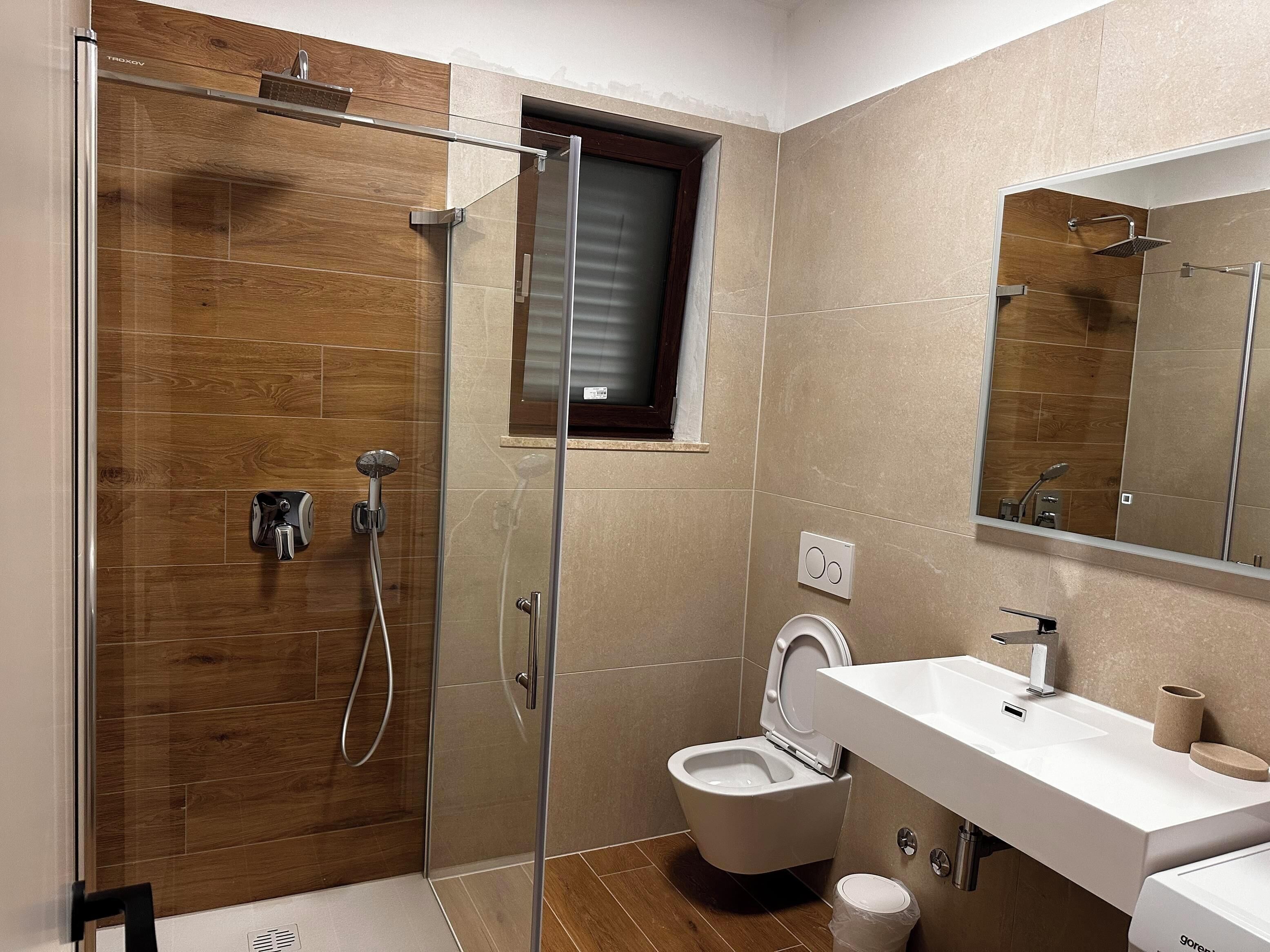 Un baño moderno con ducha de vidrio, inodoro y lavamanos.