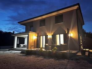 A modern two-story house with a covered patio area, large windows, and outdoor lighting. - Apartments Robi 2 (Rovinj)