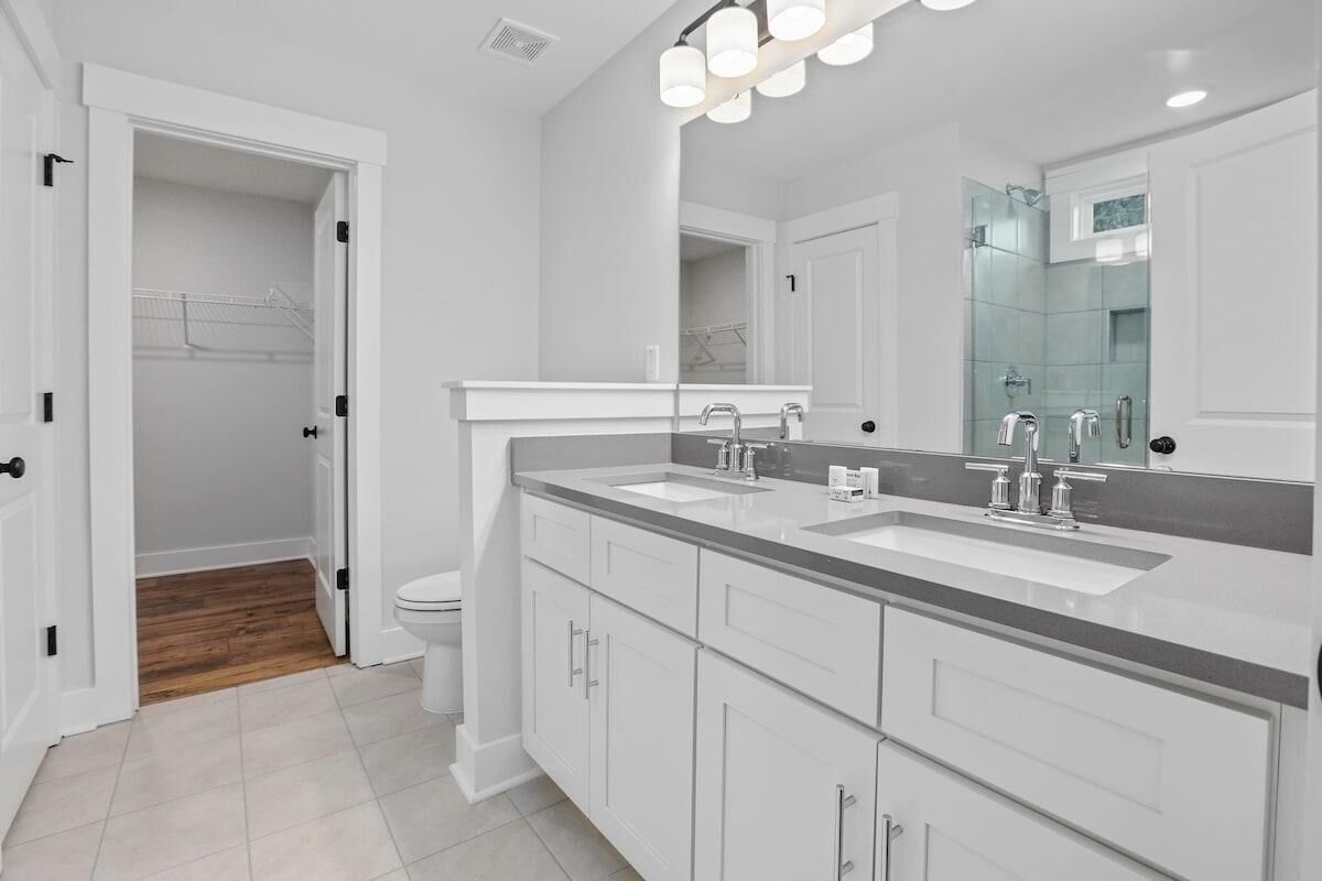 Une salle de bain moderne avec un meuble-lavabo à deux vasques, un grand miroir et un dressing.