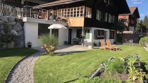 Et toetagers hus med balkon, stenvæg og velplejet græsplæne.