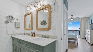 Une salle de bain avec deux lavabos, un miroir et un ventilateur de plafond.