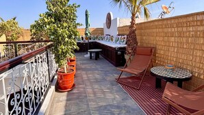 A rooftop terrace with a seating area, potted plants, and a view of the city skyline. - Magnificent Riad Kechmya 5 suites bassin Rooftop Proche Jemaa El Fna Majorelle  (Marrakesh)