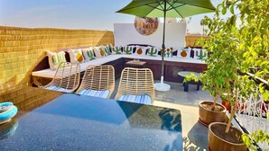 A rooftop terrace with a seating area, a table, and a large umbrella. - Magnificent Riad Kechmya 5 suites bassin Rooftop Proche Jemaa El Fna Majorelle  (Marrakesh)
