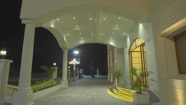 A covered outdoor area with a stone floor, white columns, and a glass canopy. - HOTEL RATNA VILAS PALACE (Rajkot)