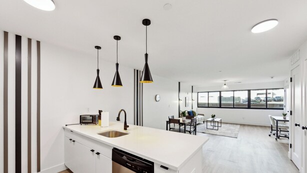 A modern kitchen with a central island, built-in appliances, and pendant lighting.