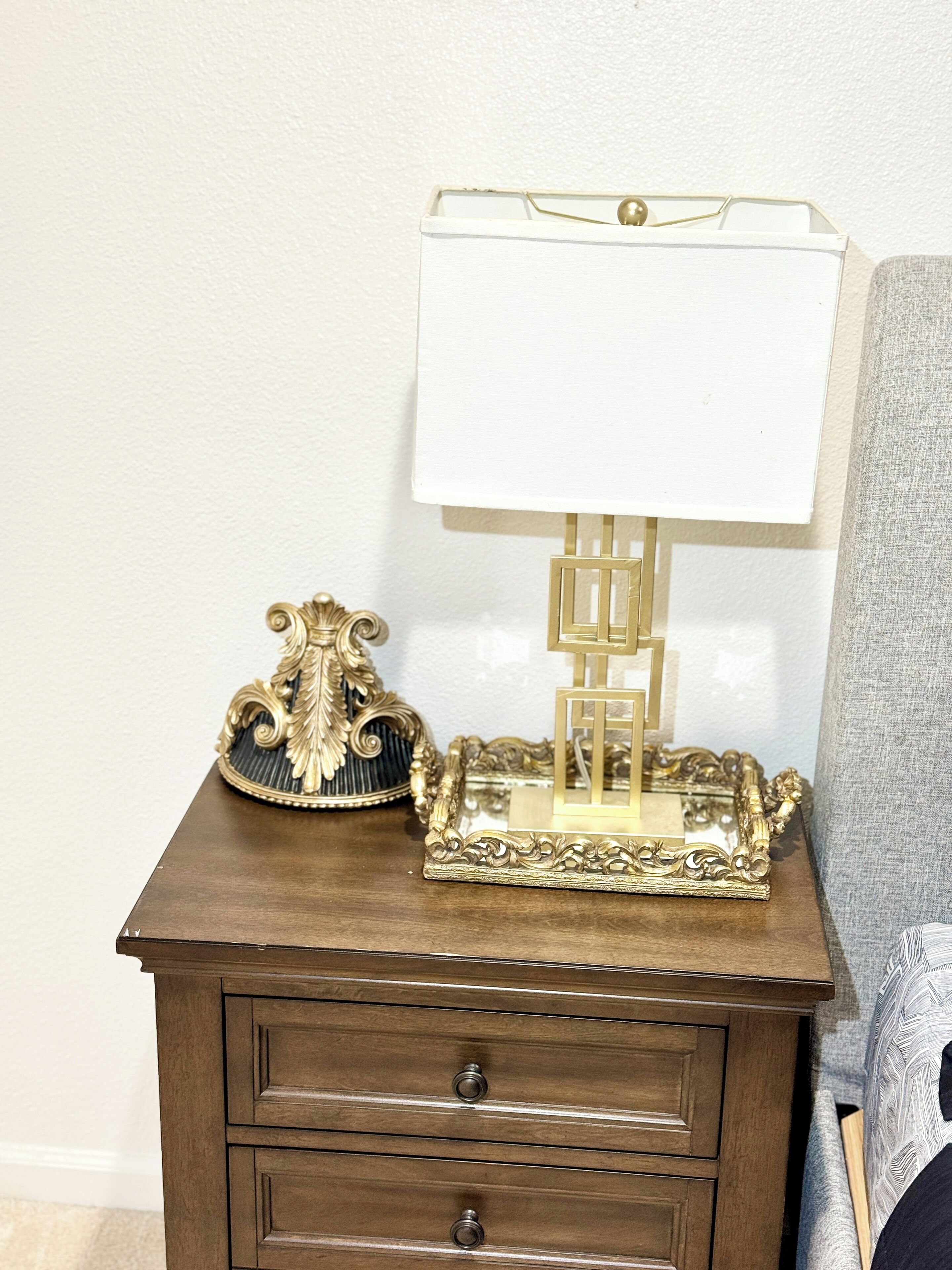 A wooden nightstand with a lamp and decorative items.